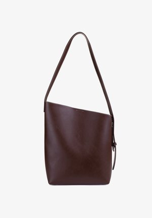Sac seau en cuir marron avec une large sangle et un bord supérieur incliné, avec un détail de boucle latérale.