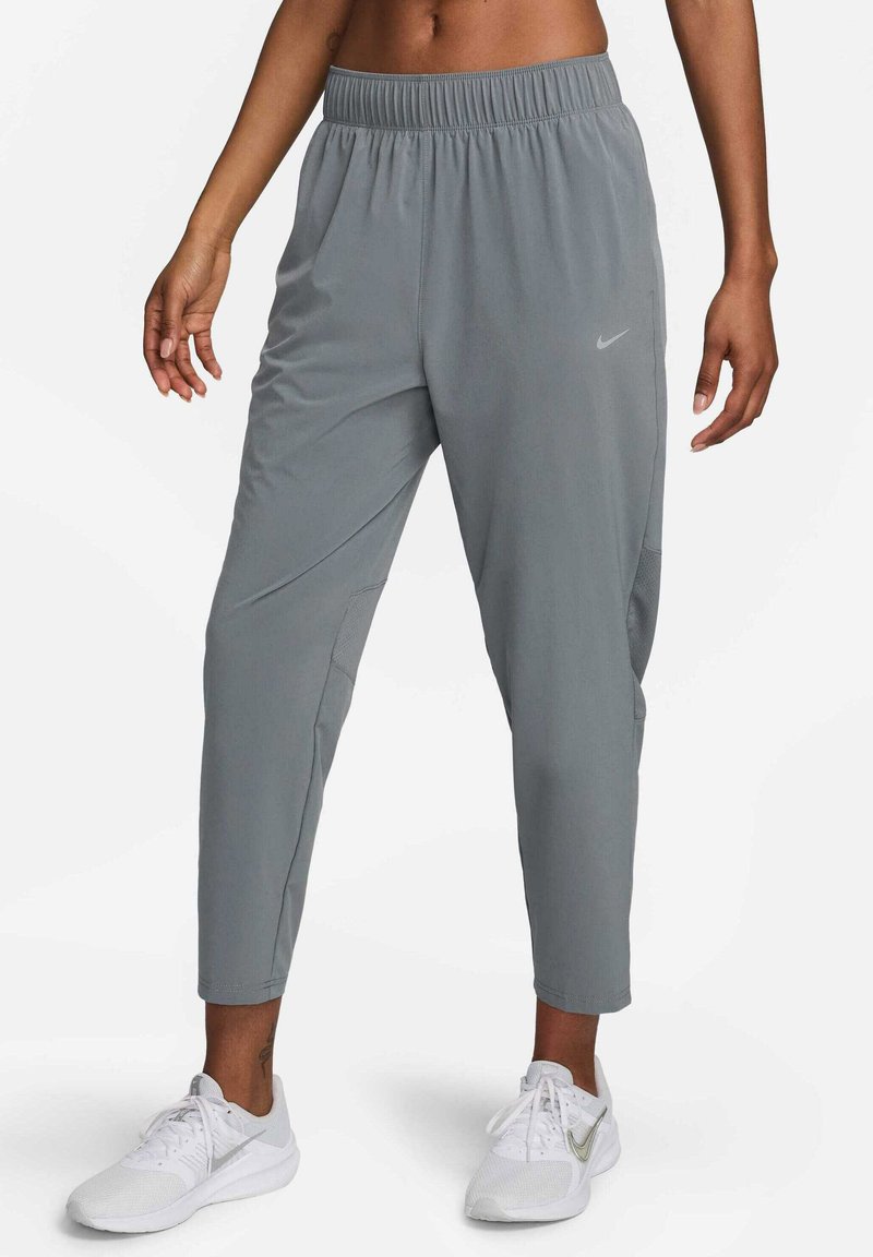 Graue Sporthosen mit elastischem Bund, schmal zulaufenden Beinen und seitlichen Netz-Einsätzen. Nike-Logo auf dem linken Oberschenkel. Getragen mit weißen Turnschuhen.