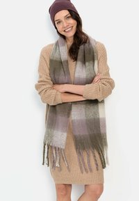 Plüschiger, karierteter Schal in Grüntönen, Lila und Creme. Besitzt lange, fransige Kanten für zusätzliche Textur. Weiches Strickmaterial mit einem gemütlichen Aussehen.