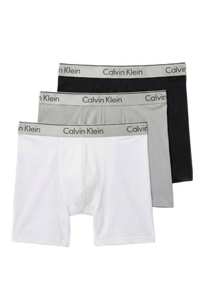 Tres pares de bóxers para hombre en blanco, gris y negro con cinturillas grises que llevan el texto "Calvin Klein".