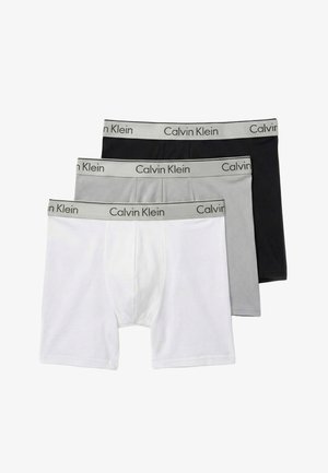 Trzy pary męskich bokserek w kolorach białym, szarym i czarnym, z szarymi pasami w talii z napisem "Calvin Klein".