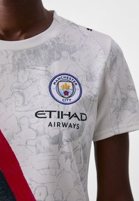 Fehér Manchester City focimez szürke absztrakt mintázattal, kék és sárga klublogóval, valamint fekete betűkkel "ETIHAD AIRWAYS" felirattal.