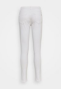 Jeans blancs ajustés avec une taille mi-haute, deux poches arrière et une texture lisse. Design minimaliste sans ornements visibles.