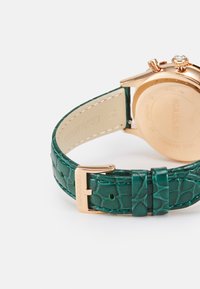 Cinturino per orologio in pelle verde con motivo coccodrillo e cassa in acciaio inossidabile dorato, caratterizzato da un cristallo decorativo e una fibbia metallica sicura.