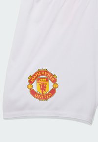 Bijele sportske kratke hlače s vezanim crvenim i žutim Logan Manchester Uniteda na donjoj lijevoj strani. Mekana, prozračna tkanina.