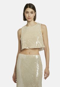 Beiger Pailletten-Crop-Top mit kastigem Schnitt und strukturiertem Oberflächenmaterial. Kombiniert mit einem passenden, mit Pailletten besetzten Rock für einen abgestimmten Look.