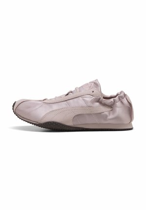 Jasnoróżowy sneaker Puma z miękką skórzaną cholewką, czarną teksturowaną podeszwą, wiązaniem na sznurowadła i elastycznym kołnierzem wokół pięty, widoczny z boku.