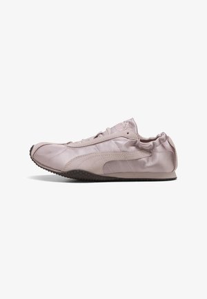 Ανοιχτό ροζ αθλητικό παπούτσι Puma με μαλακό δέρμα επάνω μέρος, μαύρη υφασμάτινη σόλα, σχέδιο με κορδόνια και ελαστικό κολάρο φτέρνας, εμφανισμένο από το πλάι.