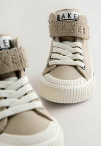 Beige high-top sneakers met een textuurafwerking, witte veters en branding op de band. Heeft een rubberen zool met ribbels.
