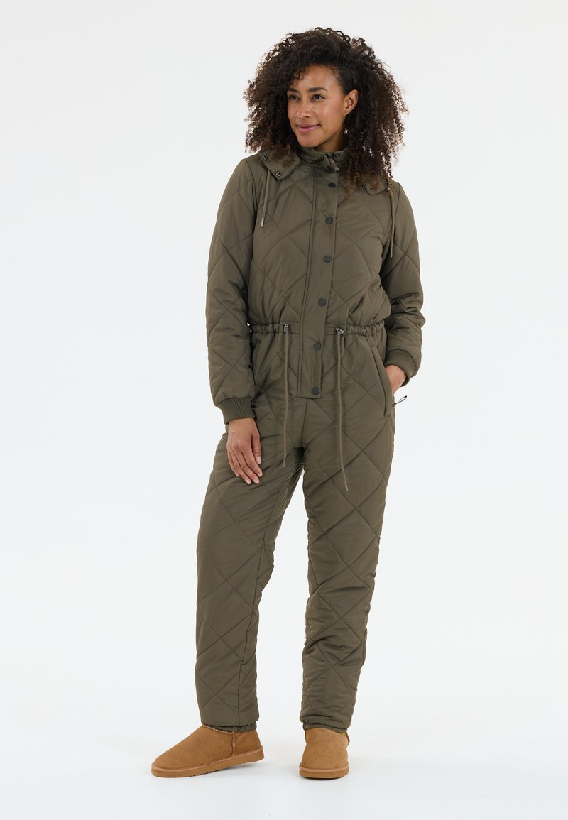 Vihreäviininvärinen tikattu haalari, jossa on korkea kaulus, säädettävä kiristysvyötärö ja napit. Yhdistetty vaaleanruskeisiin, pehmeisiin saapastyyppisiin kenkiin.