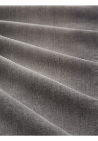 Tissu gris doux avec une texture fine visible, délicatement plié en plusieurs couches parallèles.