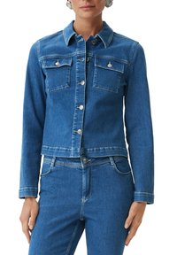 Jeansjacka i medelblått, med en kortad design, två bröstfickor, knappstängningar och vita sömnadsdetaljer.