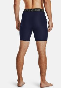 Marinefarbene Stretch-Shorts mit tailliertem Schnitt, ausgestattet mit einem schwarzen elastischen Bund mit "UNDER" Branding, glatter Textur und einer Länge bis zur Mitte des Oberschenkels.