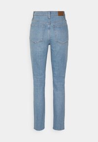 Jeans de cintura alta azul claro com uma silhueta ajustada, apresentando dois bolsos traseiros e um rótulo de couro castanho na cintura.