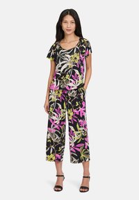 Zestaw w kwiatowy wzór z czarnym tłem, różowymi, zielonymi i białymi akcentami; luźna bluzka z szerokimi spodniami; gładka tekstura materiału.