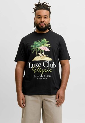 Muž s dredmi, ktorý má na sebe čierne tričko s palmami, dve plážové stoličky, pruhovaný slnečník a text "Luxe Club Utopia Established 1990."