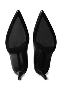 Paire de chaussures à talons hauts noires à bout pointu, vues de la semelle, avec un petit logo Calvin Klein sur chaque semelle.