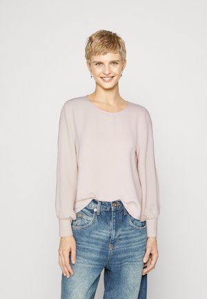 Lyserosa langermet topp med rund hals og ballongensermer, kombinert med høy midje blå denim jeans. Glatt stofftekstur.