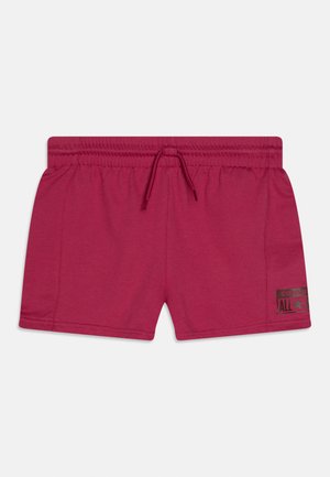 Pantalones cortos rojos con cintura elástica y cordón, con pequeño logo negro de Converse All Star en la parte inferior de la pierna izquierda.