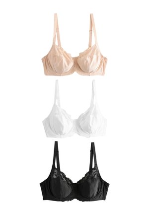 Žena sa plavom kosom do ramena koja nosi narukvicu boje breskve od čipke, blago pogleda u stranu s lagano prekriženim rukama.