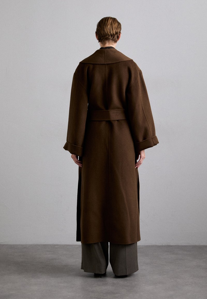 Cappotto di lana marrone con ampio colletto, maniche lunghe e vita con cintura. Presenta fessure laterali per facilitare i movimenti e una vestibilità aderente.