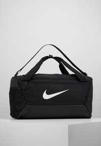 Czarna torba sportowa Nike z białym logo, wykonana z trwałego materiału, z górnymi uchwytami, zamykaną główną przegrodą oraz siateczkowymi akcentami.