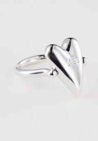 Silver ring with a large, reflective heart-shaped design engraved with the word "YES" on a white background.