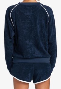 Granatowa bluza z weluru z białym lamowaniem, z okrągłym dekoltem i ściągaczami na rękawach, w komplecie z pasującymi szortami z weluru.