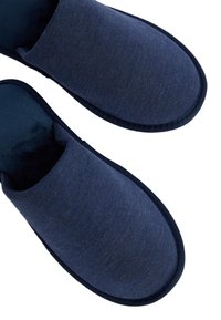 Mörkblå tygtofflor med en slät yta, öppen design, vadderad insida och mörk trim längs kanterna.