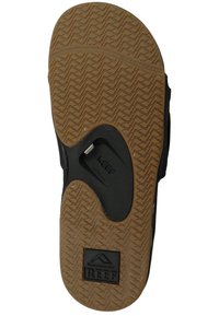 Sandale en caoutchouc noir avec une semelle extérieure texturée couleur tan, présentant un design à couches et le logo "REEF". Comprend une rainure pour l'adhérence et la flexibilité.