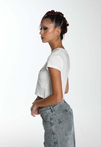 Cropped white t-shirt with short sleeves paired with high-waisted light blue jeans, featuring a relaxed fit and back pockets.