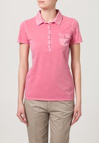 Polo shirt in cotone rosa con colletto, maniche corte, patta con bottoni e una piccola tasca sul petto. Texture morbida e design casual.