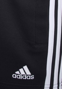 Svarta sportshorts i mjukt material, med vita sidostreck och en broderad vit Adidas-logotyp nära fållen.