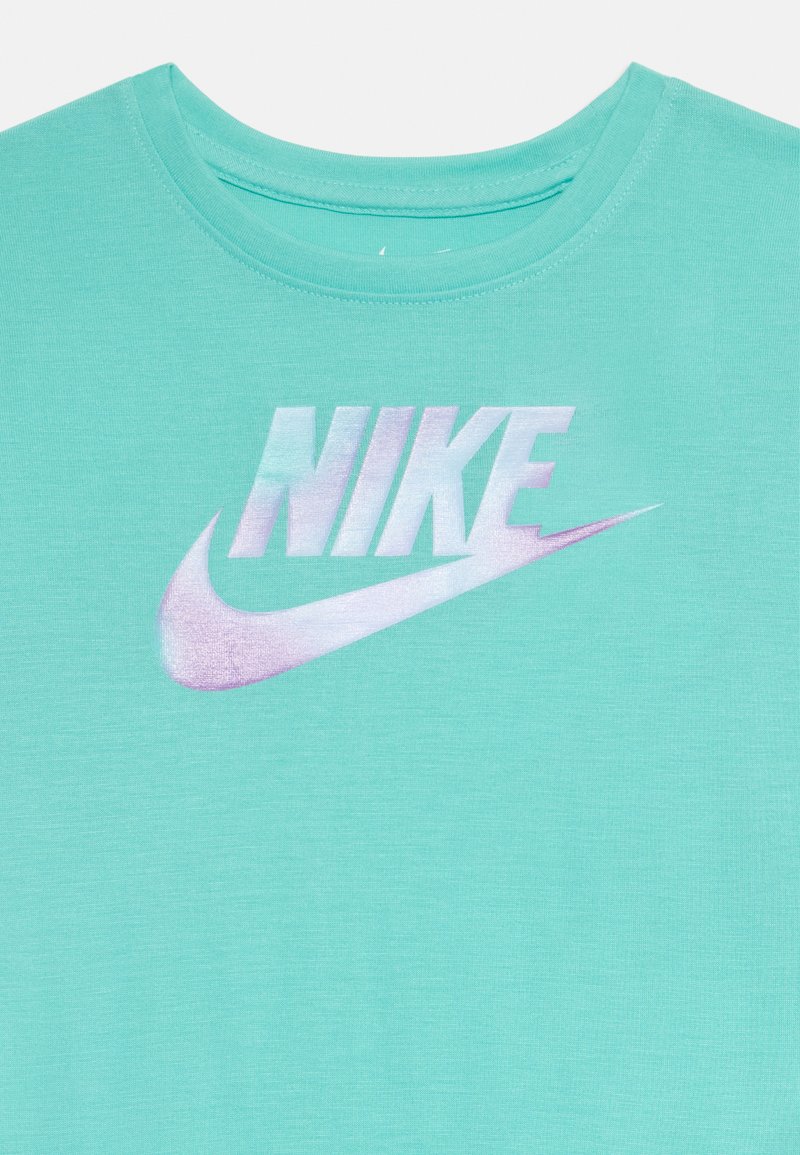 Turkusowa koszulka Nike z okrągłym dekoltem, ozdobiona metalicznym tęczowym logo Nike na piersi.