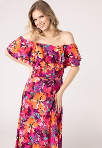 Abito floreale off-shoulder in tonalità vivaci di rosa, arancione e viola. Presenta strati di balze e una vita legata per un silhouette morbida.