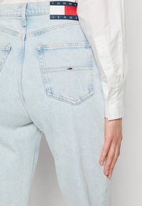 Ljust blå jeans i avslappnad passform, med en liten röd, vit och blå logopatch på bakfickan och standardstickade detaljer.