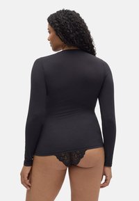 Top negro de manga larga con un diseño ajustado, combinado con lencería negra de encaje a juego, que muestra una textura suave y un estilo minimalista.