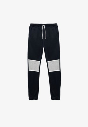 Marineblå sweatpants med snøre i taljen, der har grå paneler ved knæene. Fremstillet af blødt stof med elastiske manchetter.