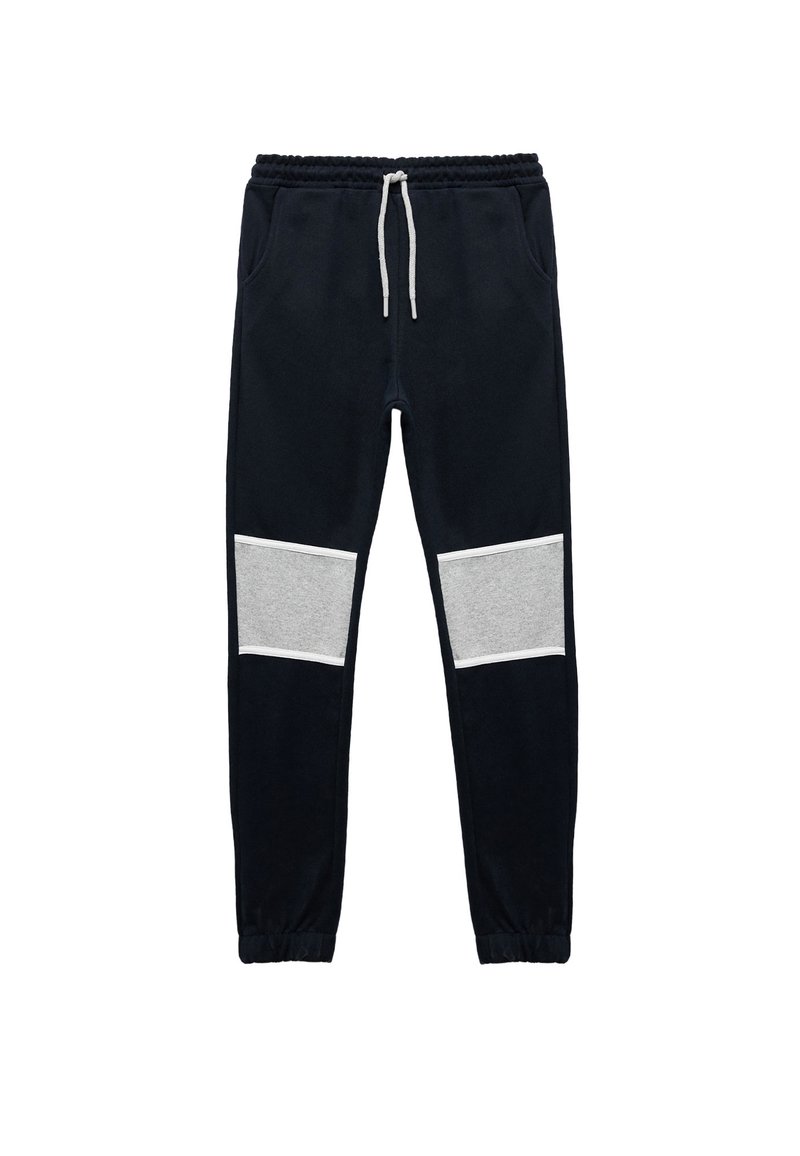 Marineblaue Jogginghosen mit einem verstellbaren Kordelzugbund, versehen mit grauen Paneelakzenten an den Knien. Hergestellt aus weichem Stoff mit elastischen Bündchen.