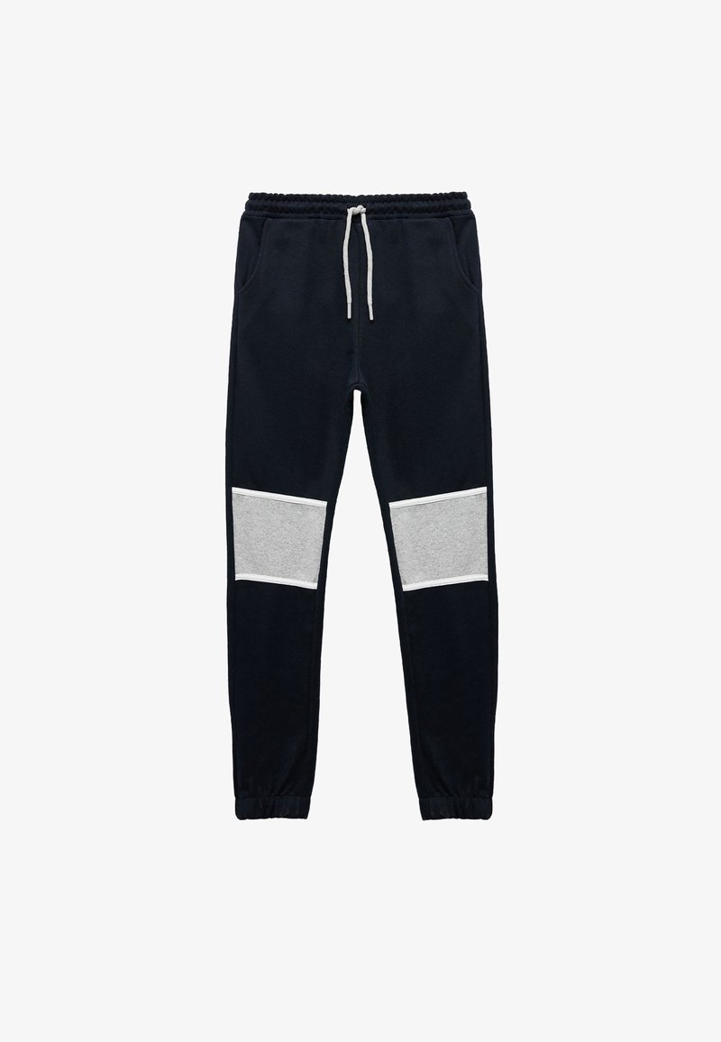 Marineblaue Jogginghosen mit einem verstellbaren Kordelzugbund, versehen mit grauen Paneelakzenten an den Knien. Hergestellt aus weichem Stoff mit elastischen Bündchen.