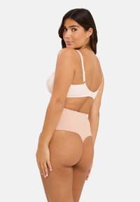 Soutien-gorge à dos en dentelle rose clair avec des bretelles ajustables, associé à une culotte haute beige au toucher doux et sans coutures visibles.