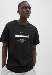 Sort bomulds t-shirt med frontgrafik tekst "JACK & JONES" og yderligere designdetaljer. Korte ærmer og afslappet pasform.