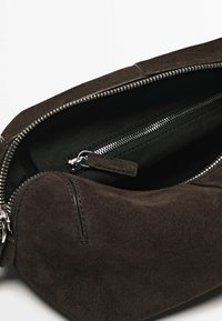 Borsa a tracolla in suede marrone con zip sulla parte superiore, dotata di una fodera interna liscia e di una tasca con zip aggiuntiva per una migliore organizzazione.