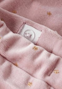 Mehak pink tkanina z majhnimi zlatimi zvezdastimi vzorci in nastavljivim belim elastičnim trakom s prišito gumbo.