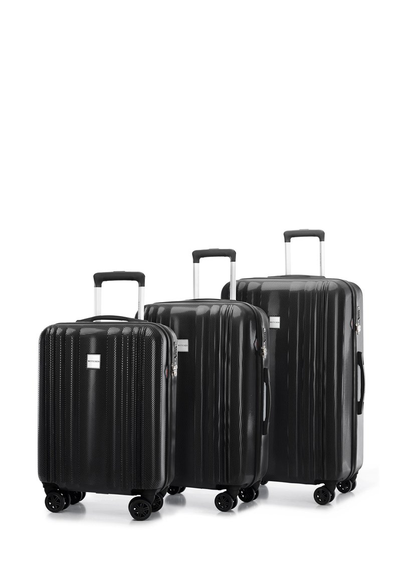 Drie zwarte harde koffers in verschillende maten, met verticale ribbelstructuur, uitschuifbare handvaten en vier draaibare wielen.