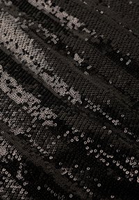 Tissu en sequins noirs avec des sequins circulaires brillants disposés en rangées. Texture lisse avec un léger effet scintillant.