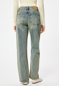 Jeans a gamba larga di colore azzurro chiaro con una finitura sbiadita, cinque tasche e un'etichetta marrone nella parte posteriore della vita. Il tessuto ha una classica texture denim.