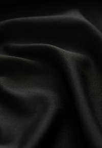 Tissu noir lisse avec des plis doux et une texture tissée subtile en gros plan.