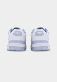 Ζευγάρι λευκών και γαλάζιων παπουτσιών Lacoste, εμφανιζόμενα από πίσω, με επενδυμένα πέλματα και υφασμένες σόλες.