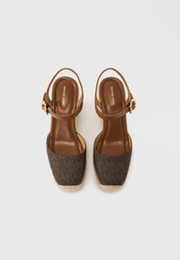 Καφέ σανδάλια εσπαντρίγια με σχεδιασμένο σκούρο καφέ επάνω μέρος, εσωτερική σόλα από ανοιχτό καφέ δέρμα και λουράκι με αγκράφα. Ορατή λεπτομέρεια εξωτερικής σόλας από τζούτ.